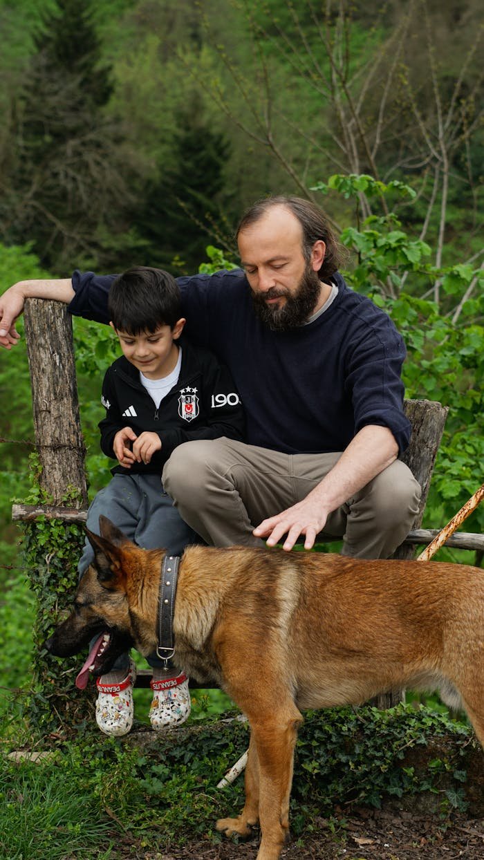 services-09 A father and son enjoy quality time outdoors with their dog on a lush green day.